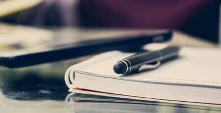 Close-up of an elegant pen resting on an open notebook in a stylish office environment.
