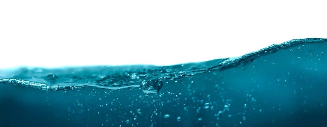 A dark blue water wave with small bubbles against a white background