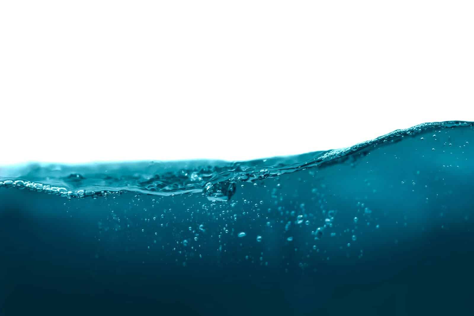 A dark blue water wave with small bubbles against a white background